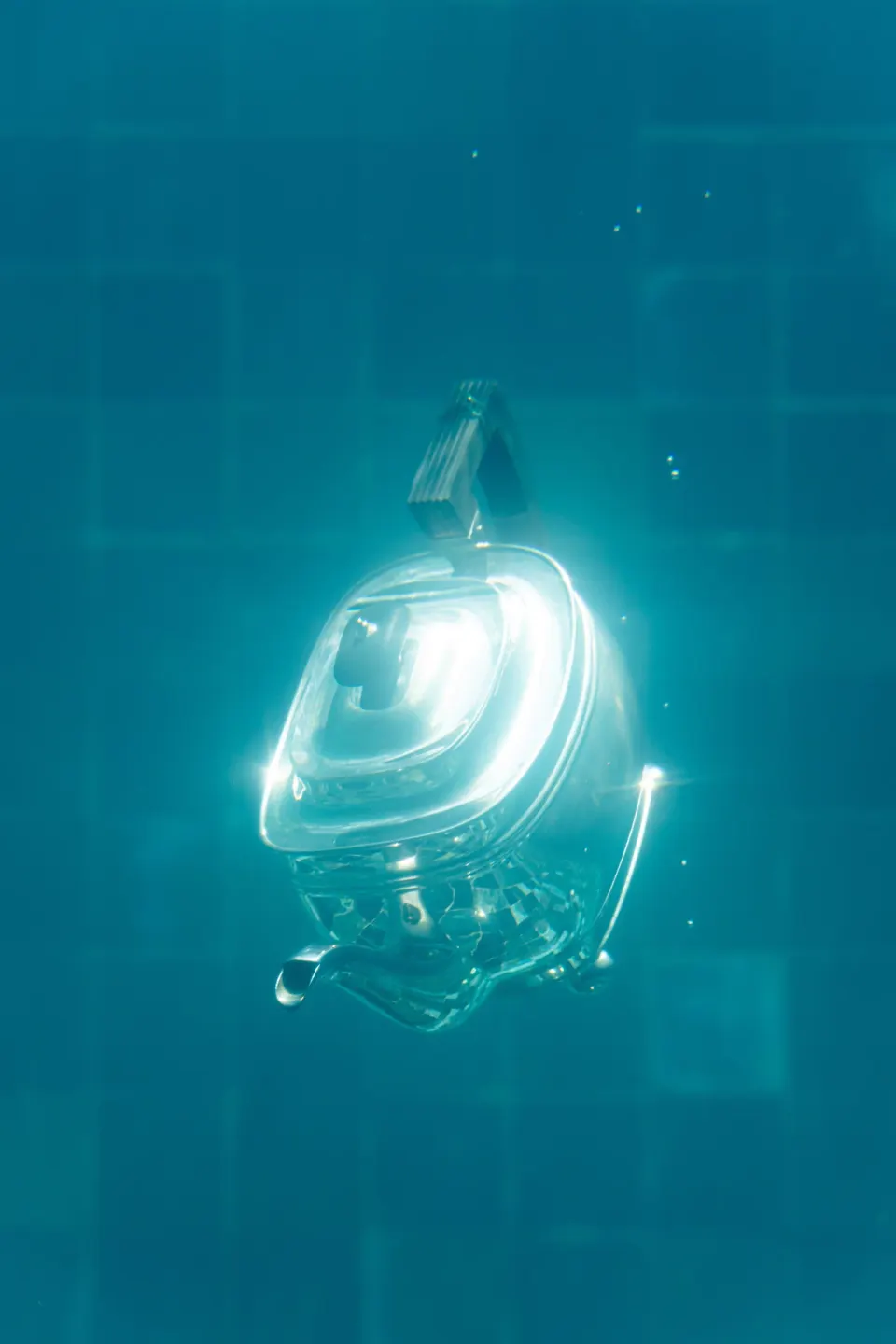 Underwater view of a glass vessel glowing in blue water.