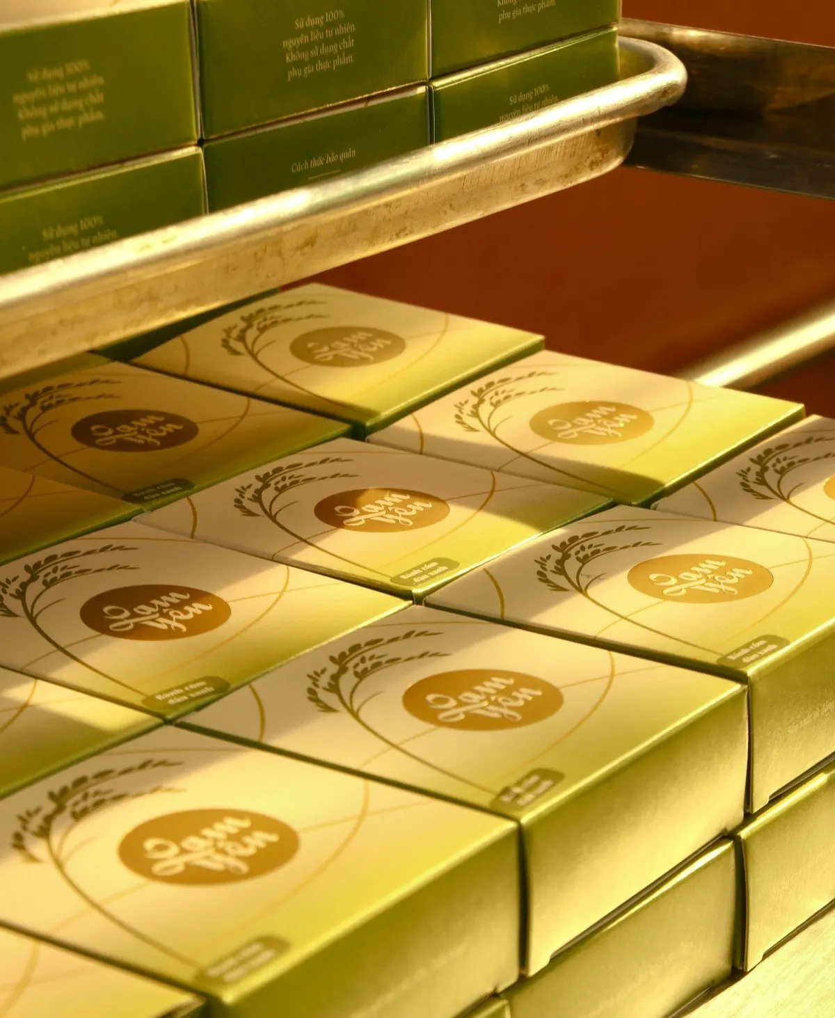Rows of green gift boxes with gold seals stacked on a shop display tray.